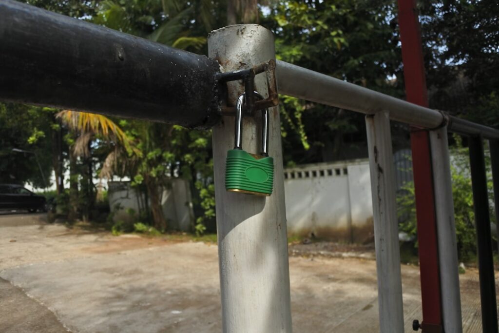 a green padlock attached to a metal fence