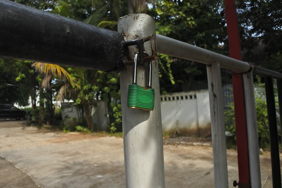 a green padlock attached to a metal fence